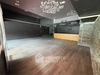 Spacious empty room with dark walls and wooden flooring, ideal for customization.