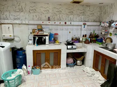 Cozy kitchen with gas stove and ample storage space, featuring a washing machine and tiled backsplash.