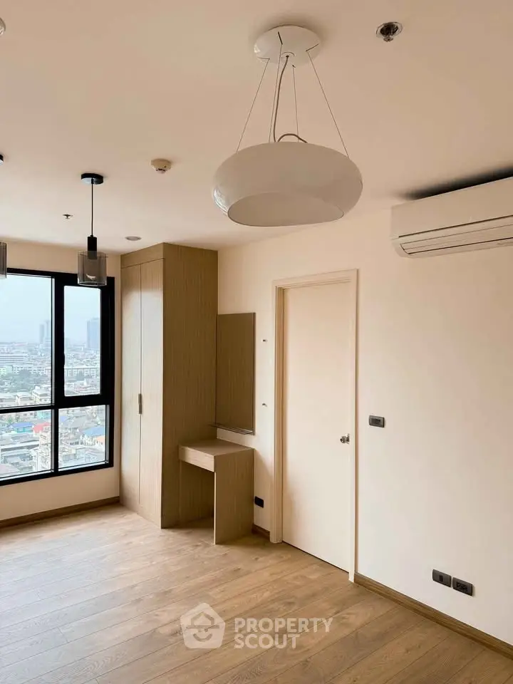Modern bedroom with wooden flooring and city view from large window.
