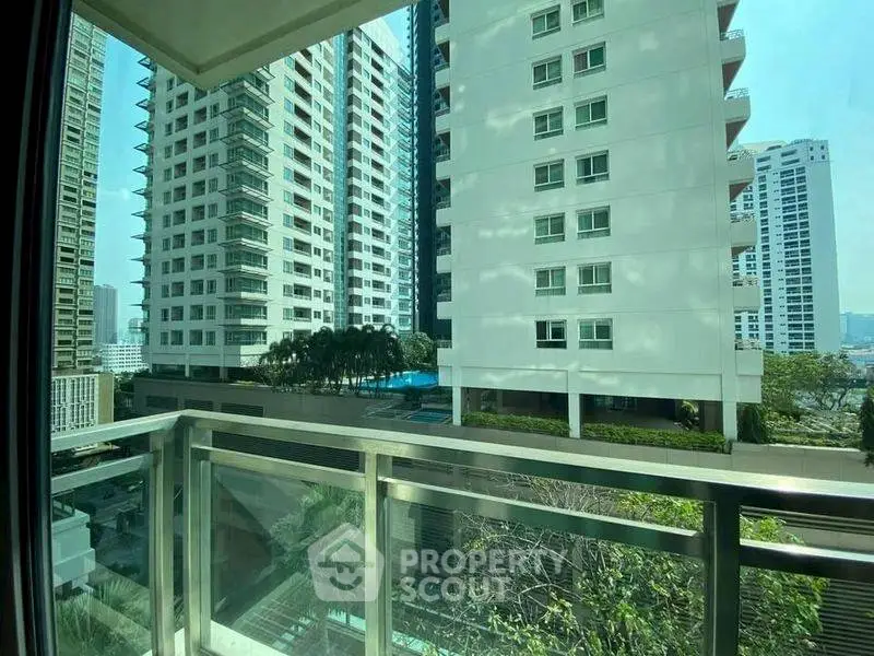 Stunning cityscape view from modern apartment balcony with lush greenery.