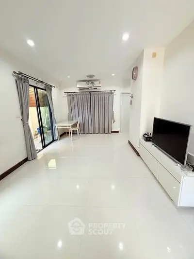Spacious modern living room with sleek white flooring and large windows for natural light.
