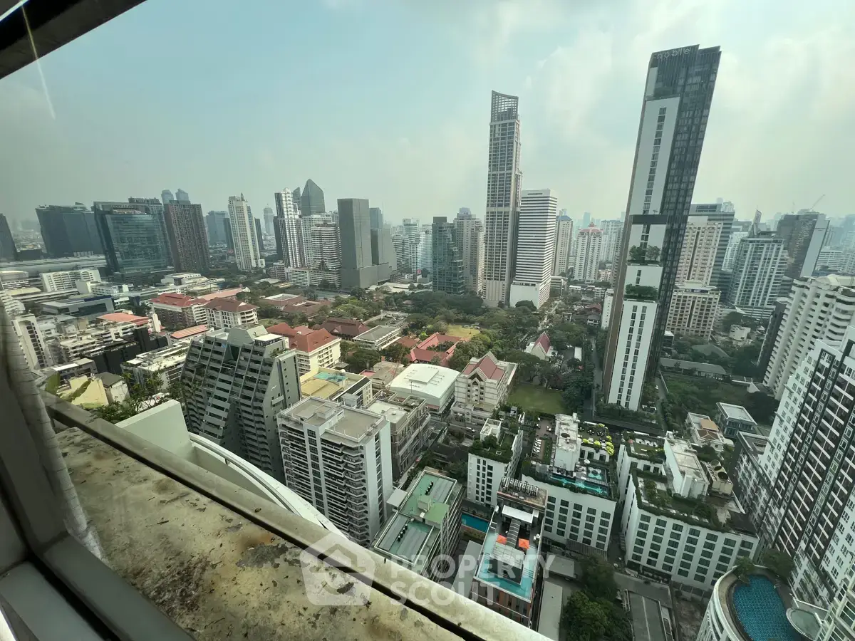 Stunning cityscape view from high-rise building showcasing urban skyline and lush greenery.