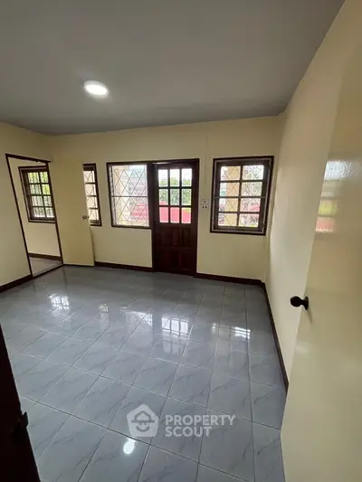 Spacious room with tiled floor and large windows in a bright, airy home.