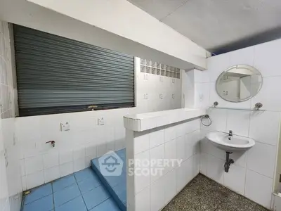 Spacious tiled bathroom with blue flooring and wall-mounted sink, ideal for modern renovation.