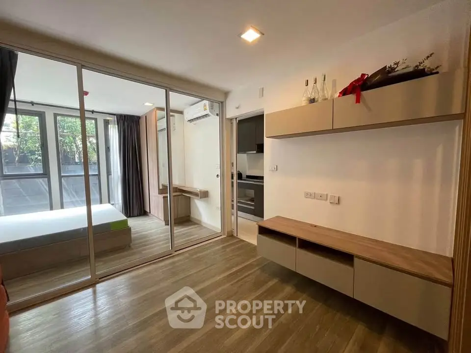 Modern apartment interior with sliding glass doors, wooden flooring, and built-in shelves.