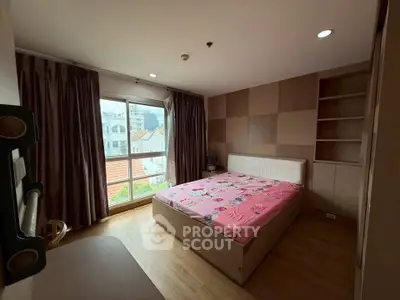 Cozy bedroom with large window and built-in storage, offering a bright and inviting atmosphere.