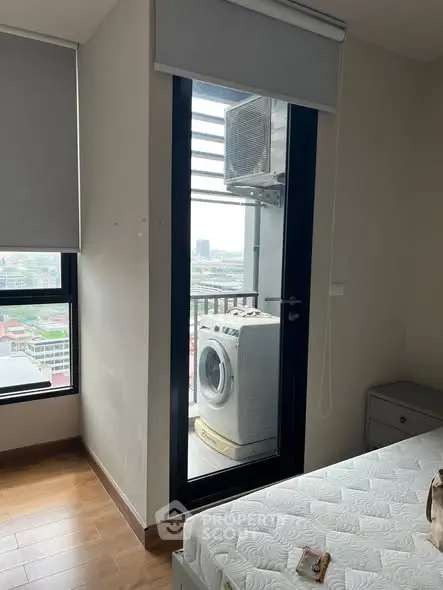 Modern bedroom with balcony view and washing machine, featuring sleek design and natural light.