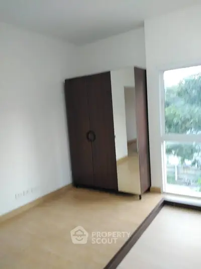 Spacious bedroom with large window and wooden wardrobe