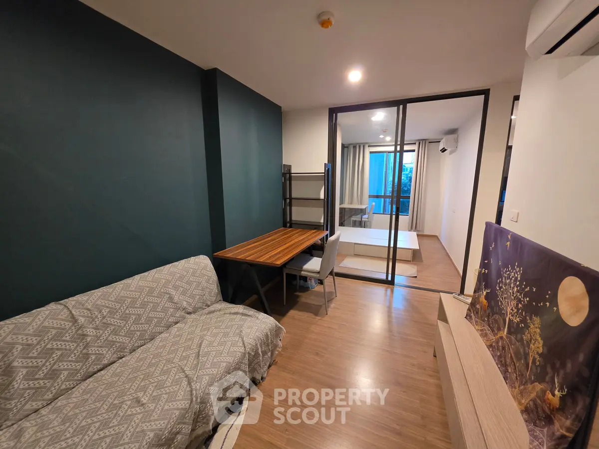 Modern living room with stylish decor and sliding glass doors leading to a cozy bedroom.