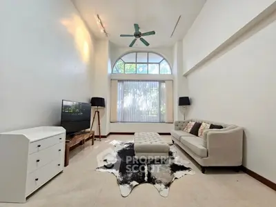 Spacious living room with high ceiling and large window, featuring modern furniture and stylish decor.