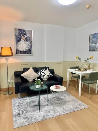 Chic living room with modern decor, featuring a black sofa, stylish artwork, and cozy dining area.