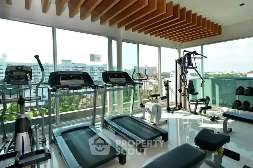 Modern gym with state-of-the-art equipment and panoramic city views in luxury apartment building.