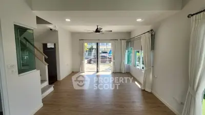 Spacious living room with wooden flooring and large windows for natural light