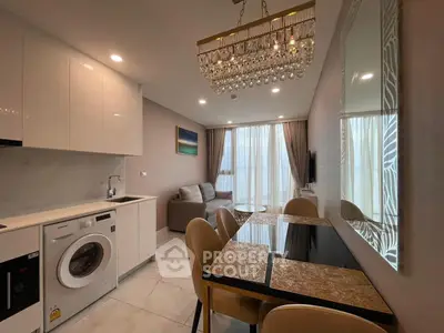 Modern open-plan living room with elegant chandelier and integrated kitchen appliances.