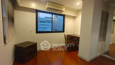 Spacious study room with wooden flooring and large window offering city views.