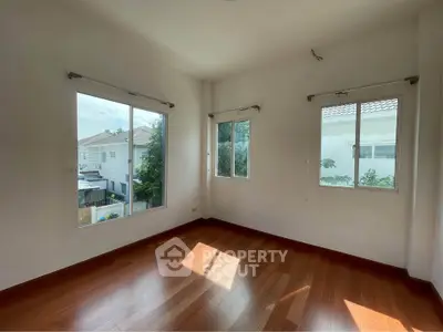 Bright empty room with wooden flooring and large windows in modern home
