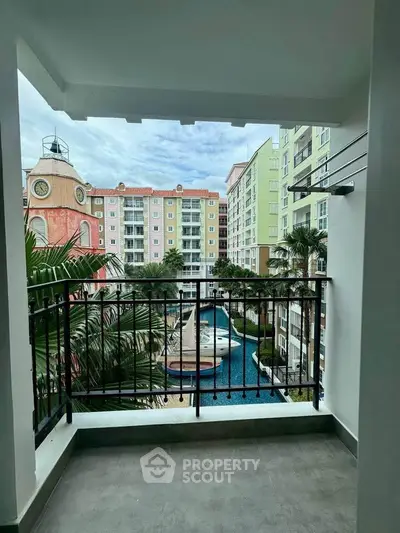 Charming balcony view overlooking colorful apartment complex with pool and lush greenery.
