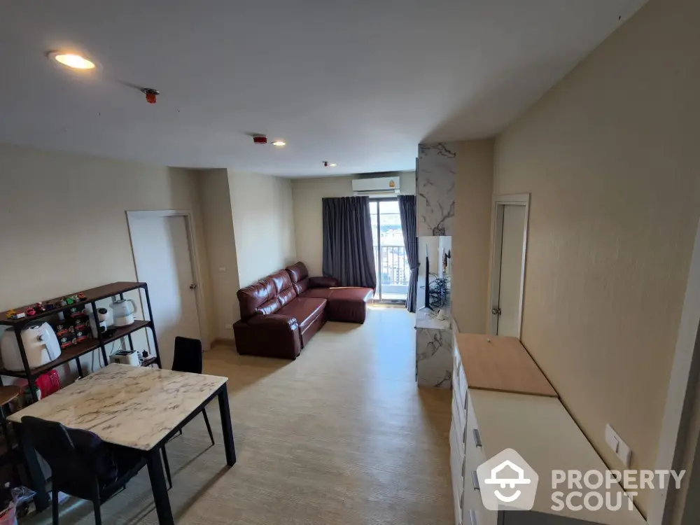 Spacious modern living room with marble table and leather sofa, featuring a balcony view.