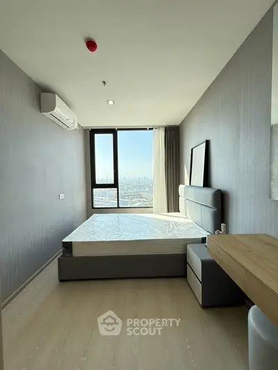 Modern bedroom with city view, featuring sleek furniture and large window for natural light.