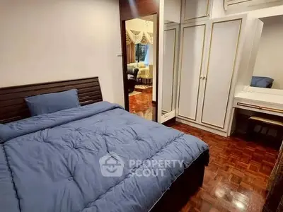 Cozy bedroom with wooden flooring and built-in wardrobe, perfect for relaxation.