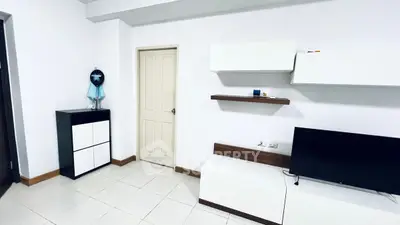Modern living room with sleek white furniture and wall-mounted shelves.
