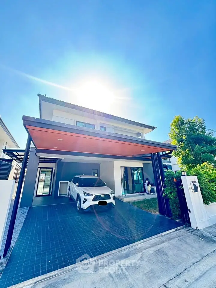 Modern two-story house with carport and sleek design under bright blue sky.