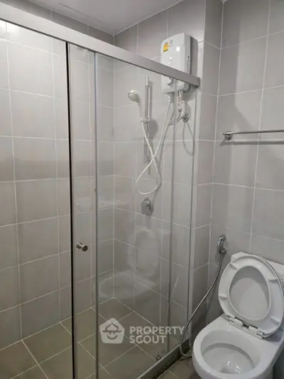 Modern bathroom with glass shower enclosure and toilet in sleek design.