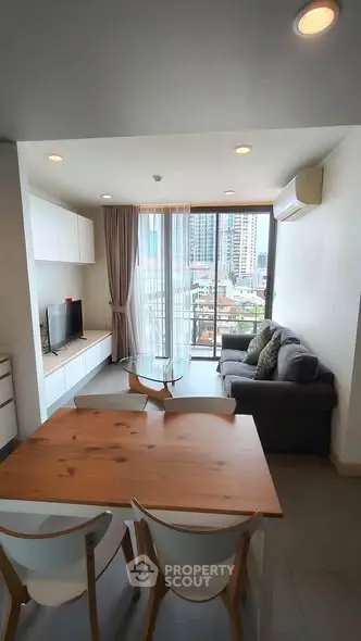 Modern living room with city view, featuring cozy seating and dining area, perfect for urban living.