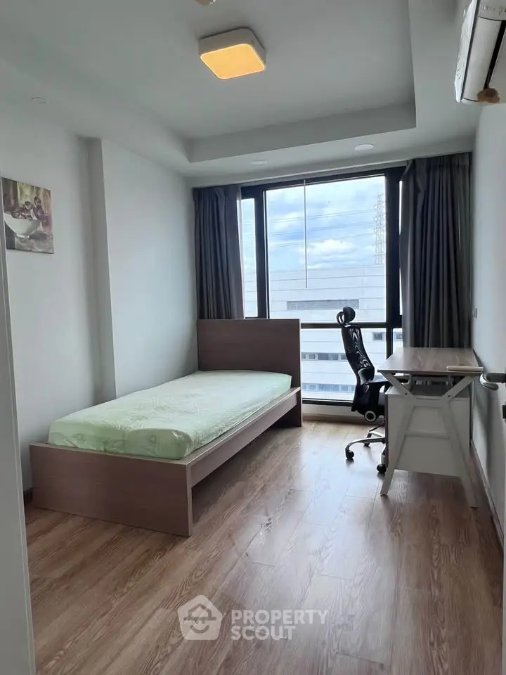Modern bedroom with large window and wooden flooring in a high-rise apartment.