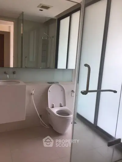 Modern bathroom with sleek fixtures and large frosted glass window
