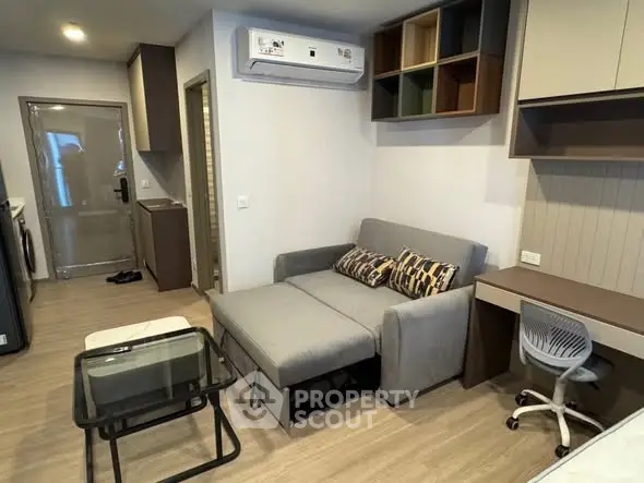 Modern living room with stylish sofa, glass table, and workspace in cozy apartment.