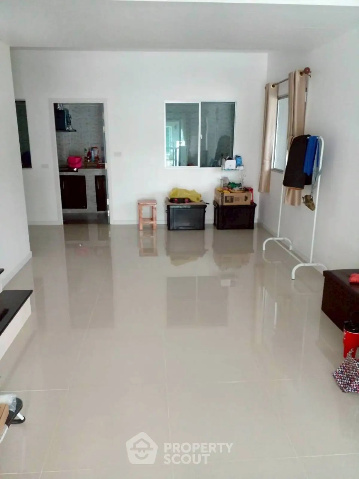 Spacious living area with glossy tiled flooring and minimal furnishings