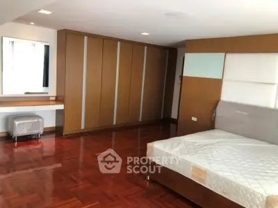 Spacious bedroom with wooden flooring and built-in wardrobe in modern apartment.