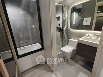 Luxurious modern bathroom with glass shower and bathtub in elegant apartment.
