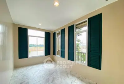 Bright room with large windows and green shutters offering scenic views, perfect for a serene living space.