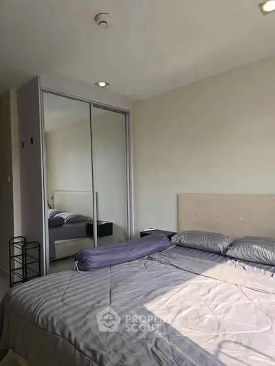 Spacious bedroom with mirrored closet and ample natural light in modern apartment.