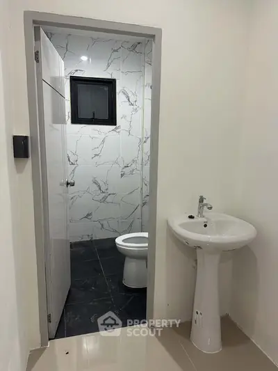 Modern bathroom with sleek white fixtures and marble tile accents, perfect for a contemporary home.