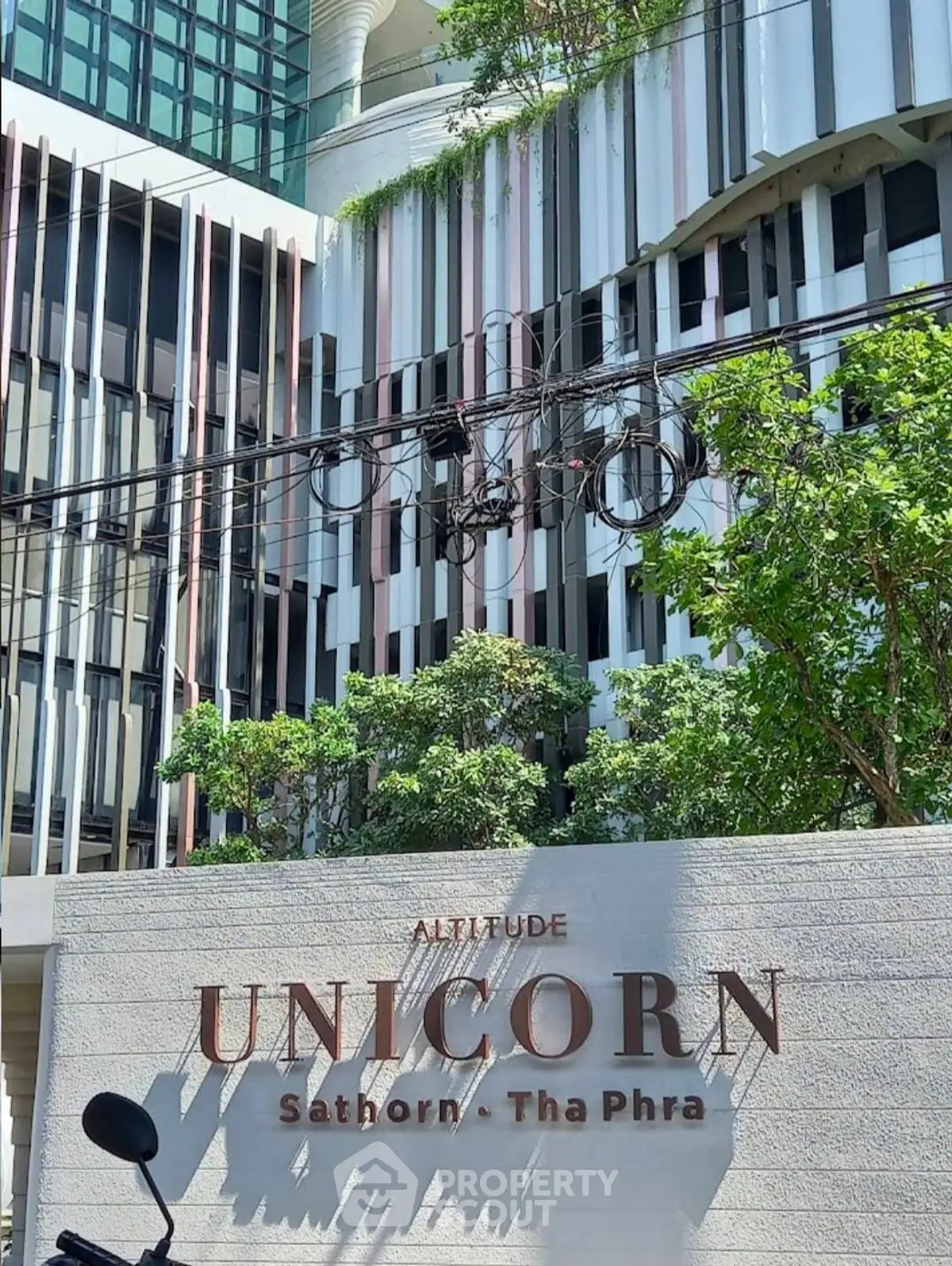 Modern architectural facade of Altitude Unicorn Sathorn Tha Phra with lush greenery.