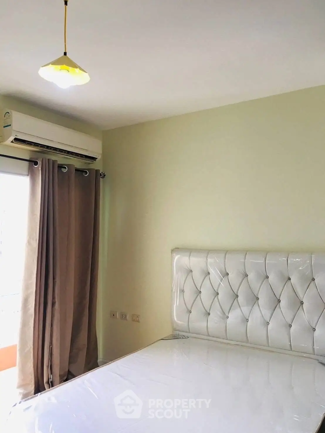 Cozy bedroom with elegant tufted headboard and air conditioning, perfect for restful nights.