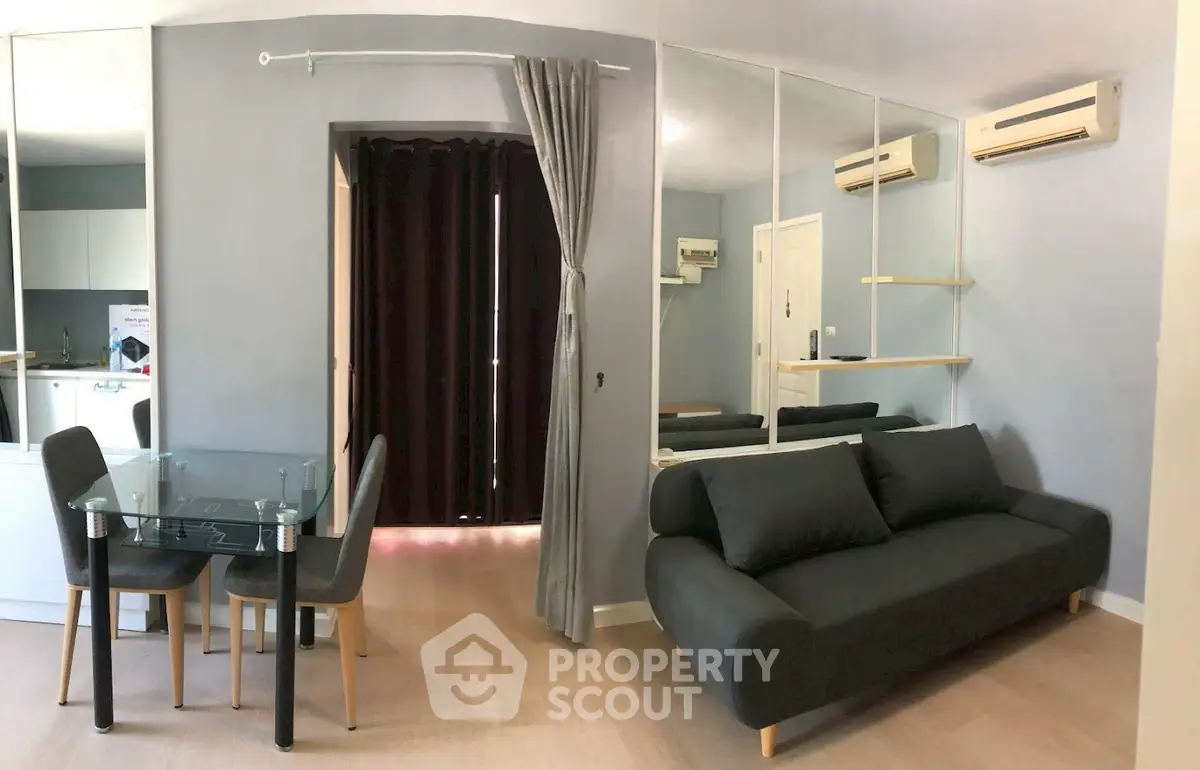 Modern living room with sleek black sofa and glass dining table in stylish apartment.