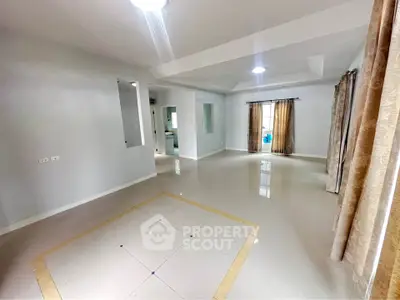 Spacious living room with elegant tile flooring and large windows for natural light.