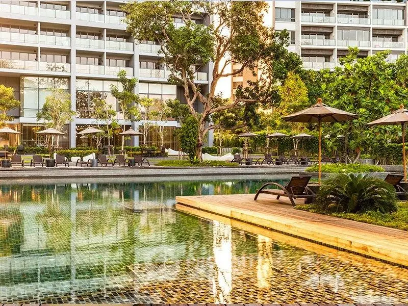 Luxurious apartment complex with serene pool and lush greenery, perfect for relaxation and modern living.