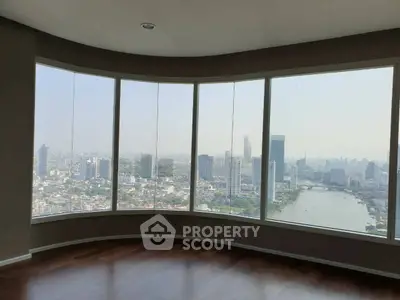 Stunning high-rise apartment with panoramic city and river views, featuring floor-to-ceiling windows and elegant hardwood floors.