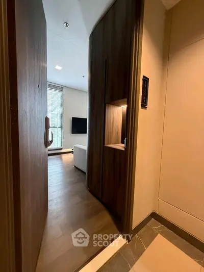 Modern apartment entrance with sleek wooden door and cozy living room view.