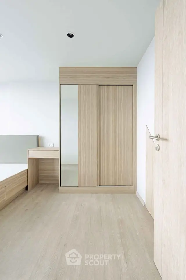 Modern minimalist bedroom with wooden flooring and built-in wardrobe.
