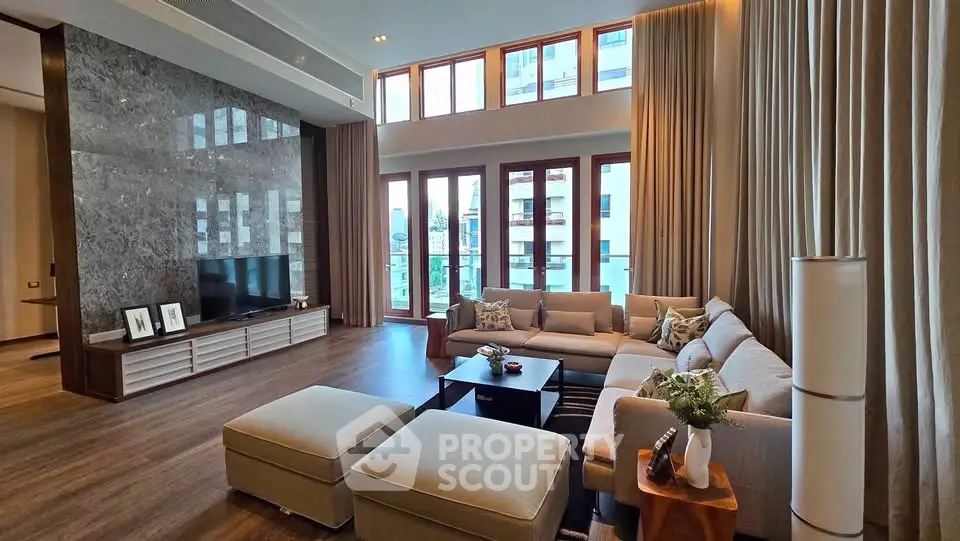 Luxurious living room with high ceilings, elegant decor, and large windows offering natural light.