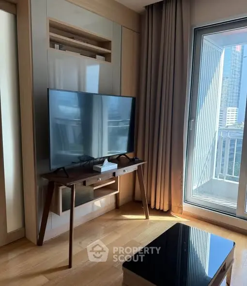 Modern living room with sleek TV stand and large window offering city view.
