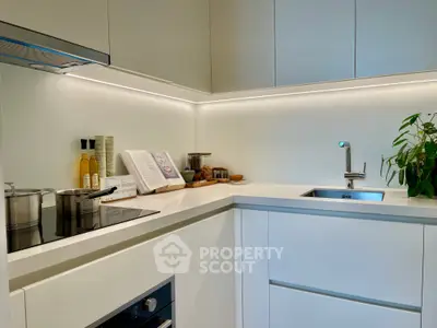Modern kitchen with sleek white cabinetry and built-in appliances, featuring an elegant open layout.