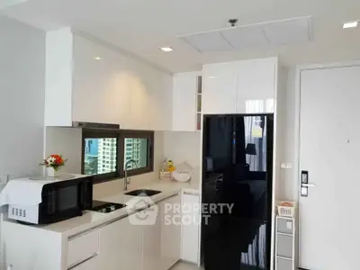 Modern kitchen with sleek white cabinets and black appliances in a stylish apartment.