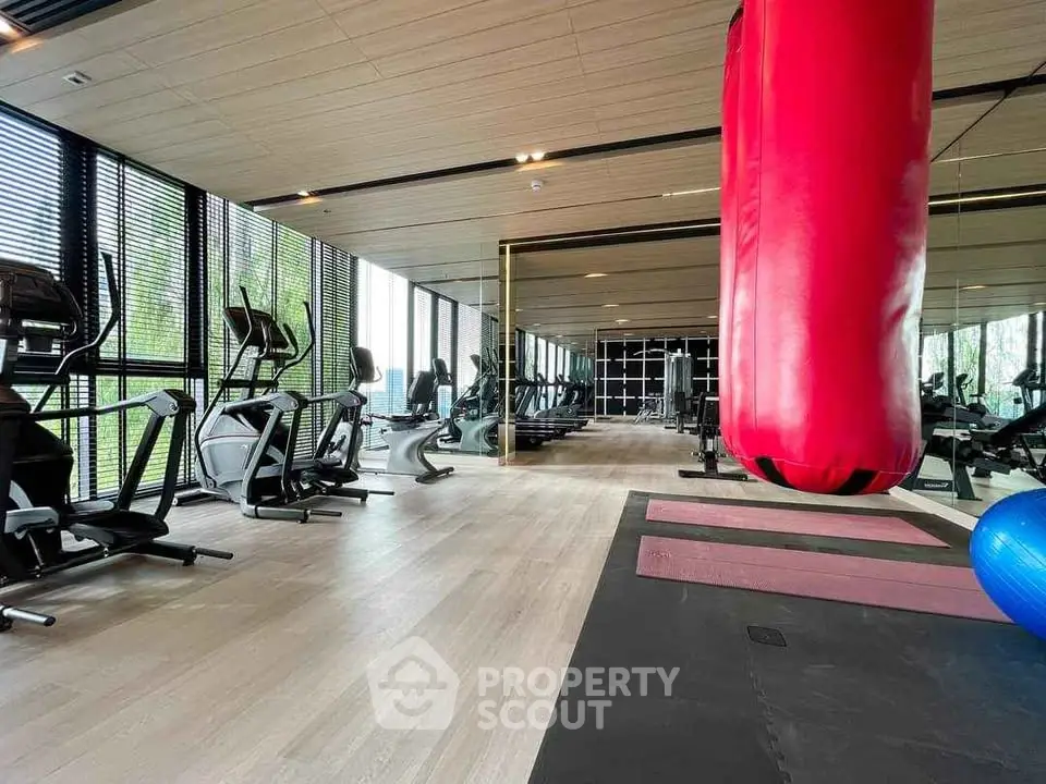 Luxurious gym with modern equipment and large windows in upscale residential building.